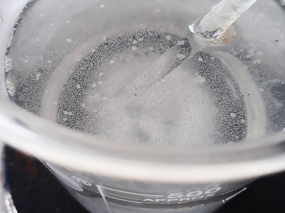 继续加热溶液，直到你看见一些小的、白色的盐薄片开始在溶液表面形成